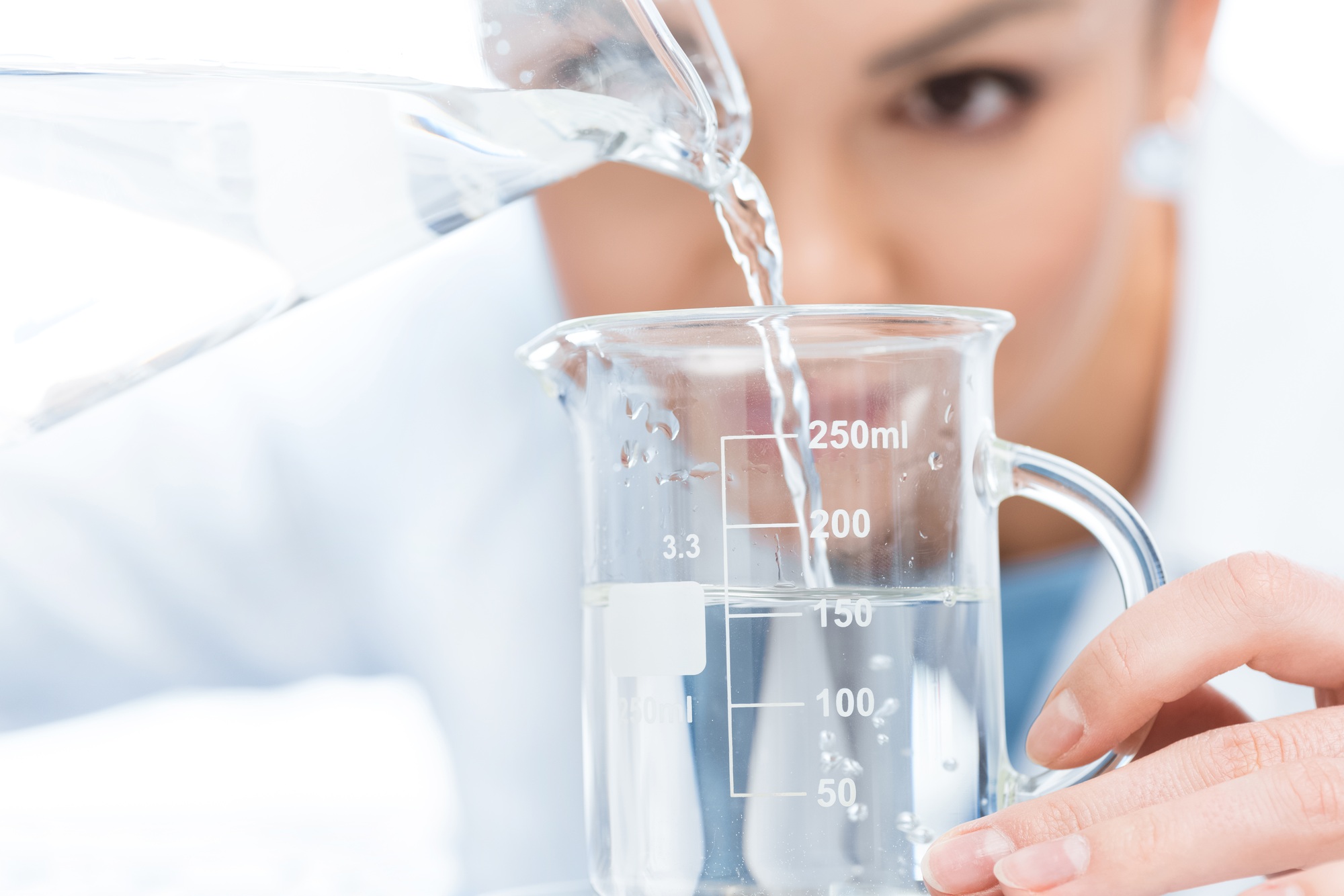 scientist pouring chemical liquid into laboratory glassware, focus on foreground