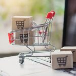 Shopping online. Cardboard box with a shopping cart logo in a trolley on laptop keyboard.